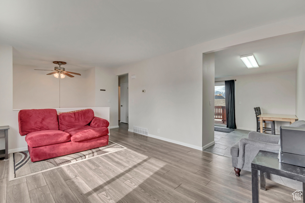 Living area with ceiling fan, baseboards, visible vents, and wood finished floors