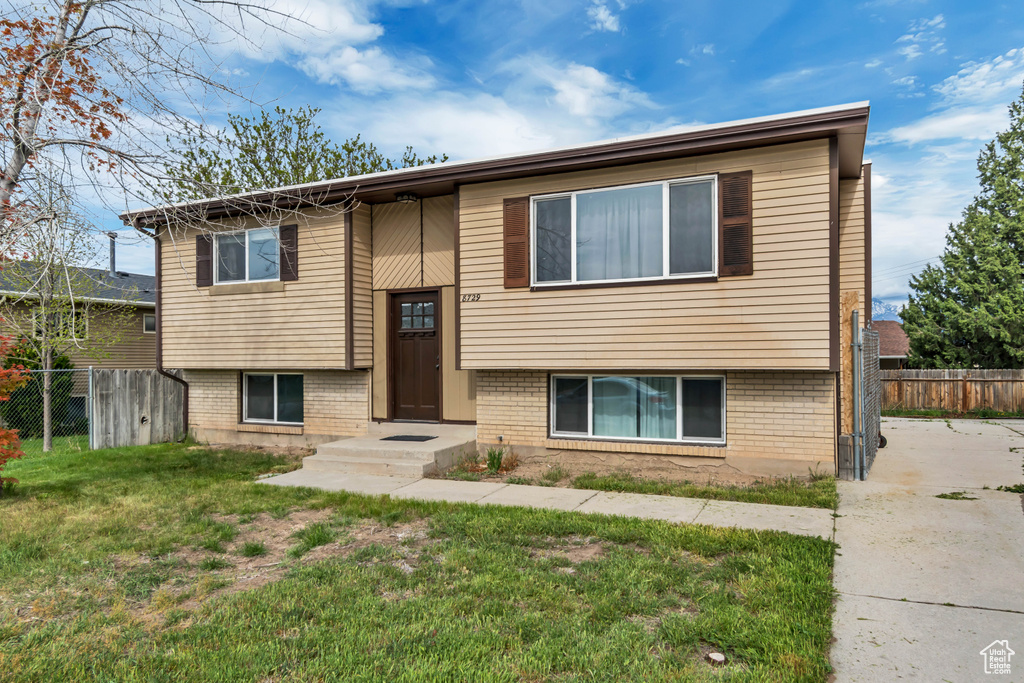 Split foyer home featuring fence, a front lawn, and brick siding