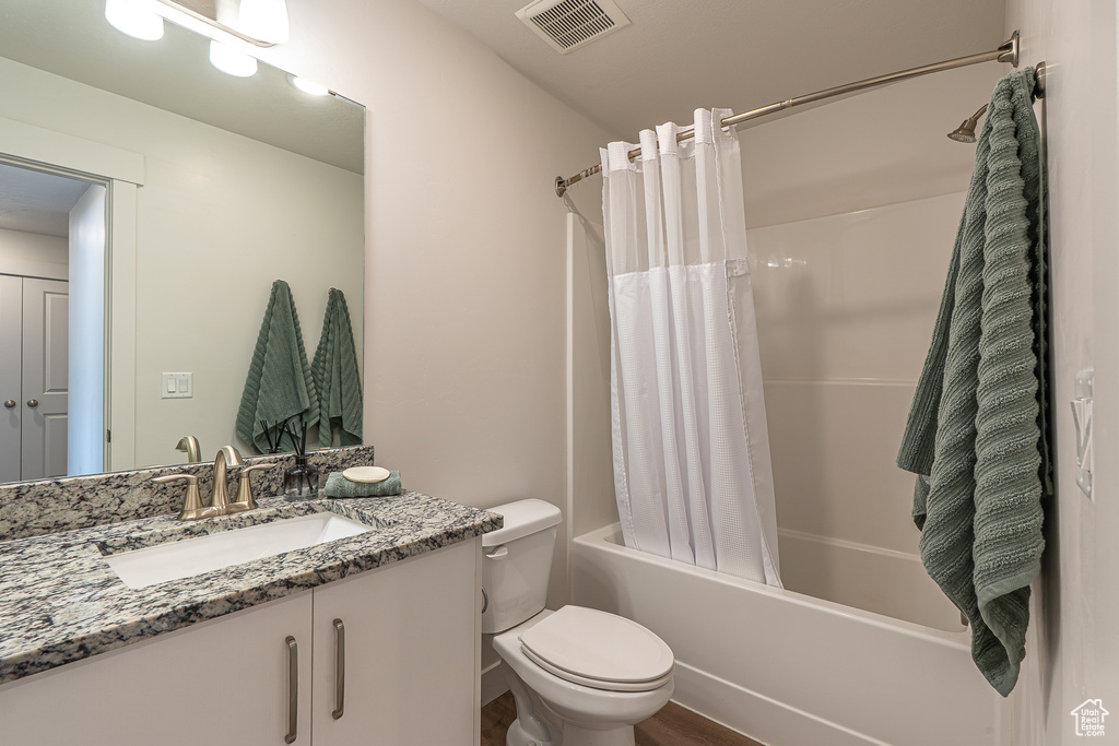 Bathroom with visible vents, vanity, wood finished floors, toilet, and shower / tub combo