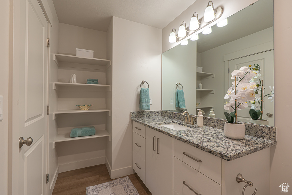 Bathroom featuring baseboards, wood finished floors, and vanity
