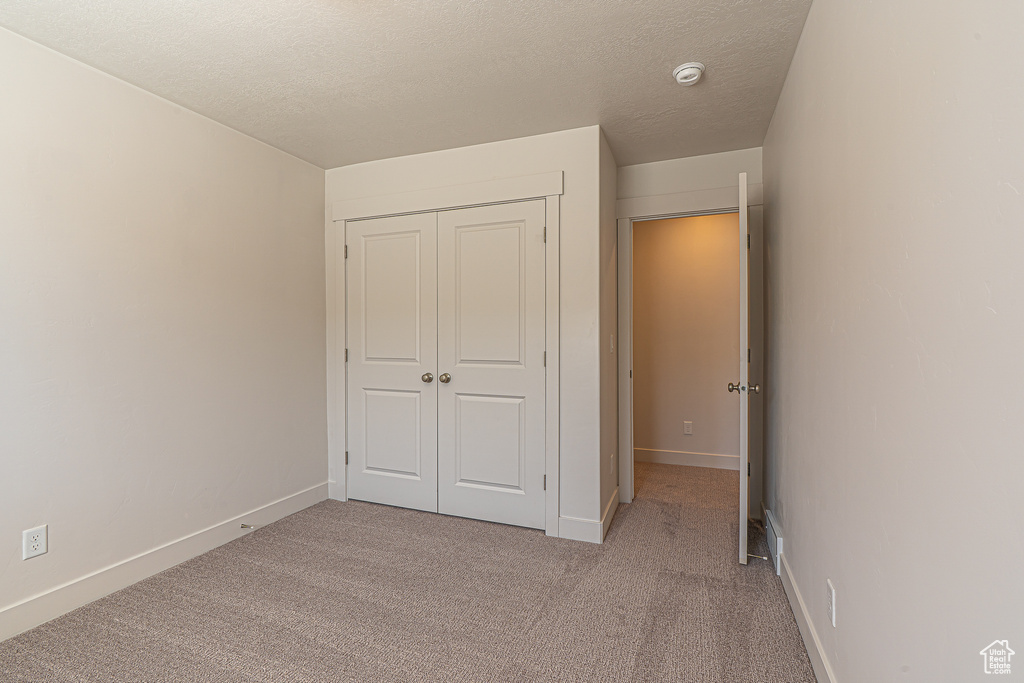 Unfurnished bedroom featuring baseboards, carpet, and a closet