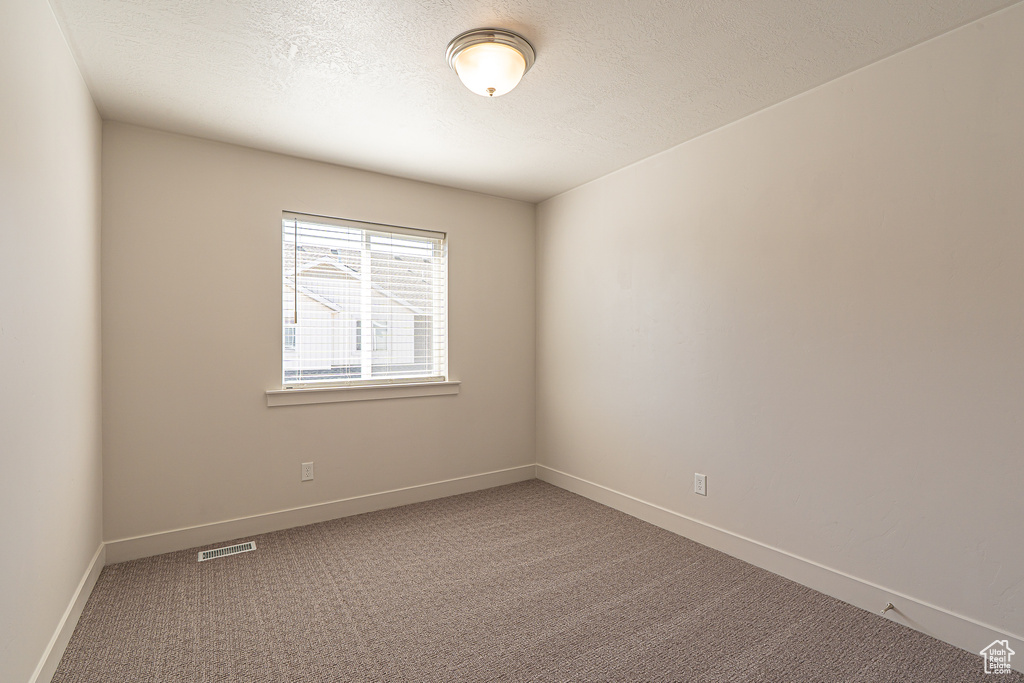 Unfurnished room with carpet floors, baseboards, a textured ceiling, and visible vents