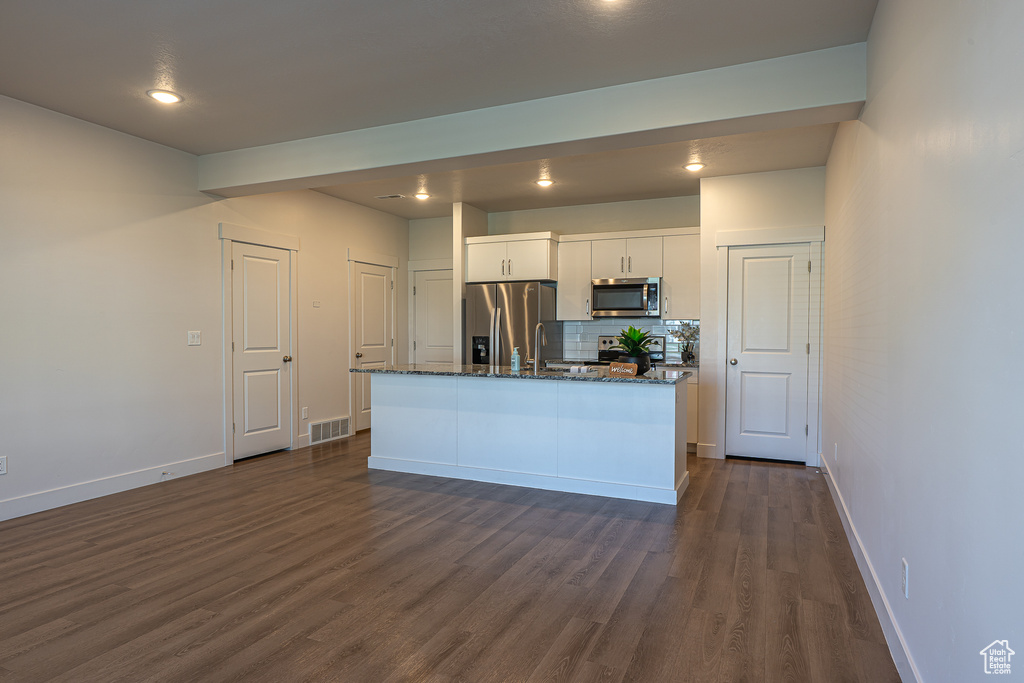 Kitchen with backsplash, visible vents, dark wood-style floors, stainless steel appliances, and white cabinetry
