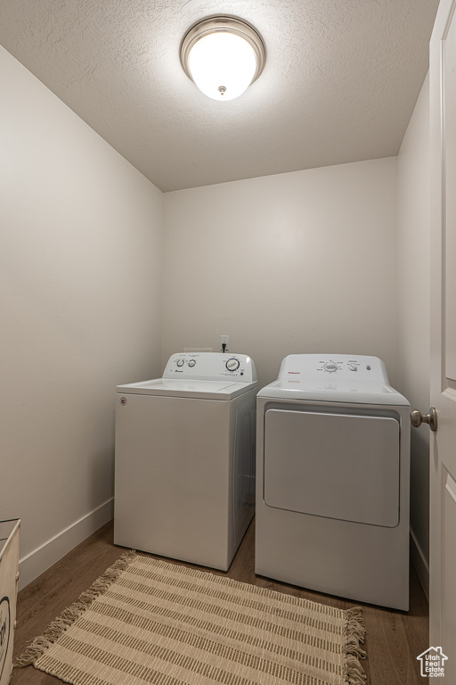 Washroom featuring baseboards, laundry area, wood finished floors, and washing machine and clothes dryer