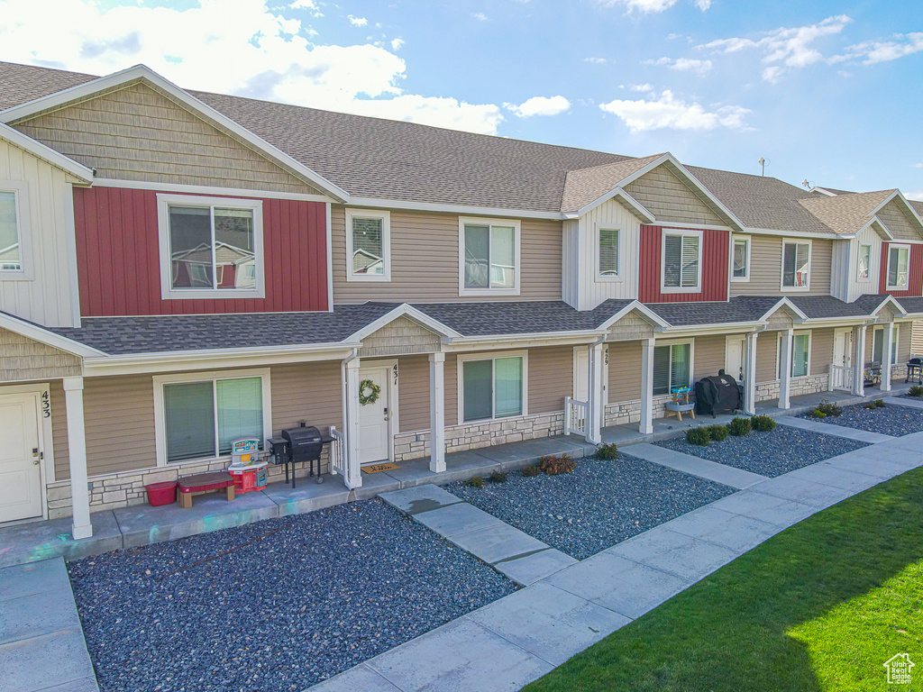 Multi unit property featuring a shingled roof, covered porch, and stone siding