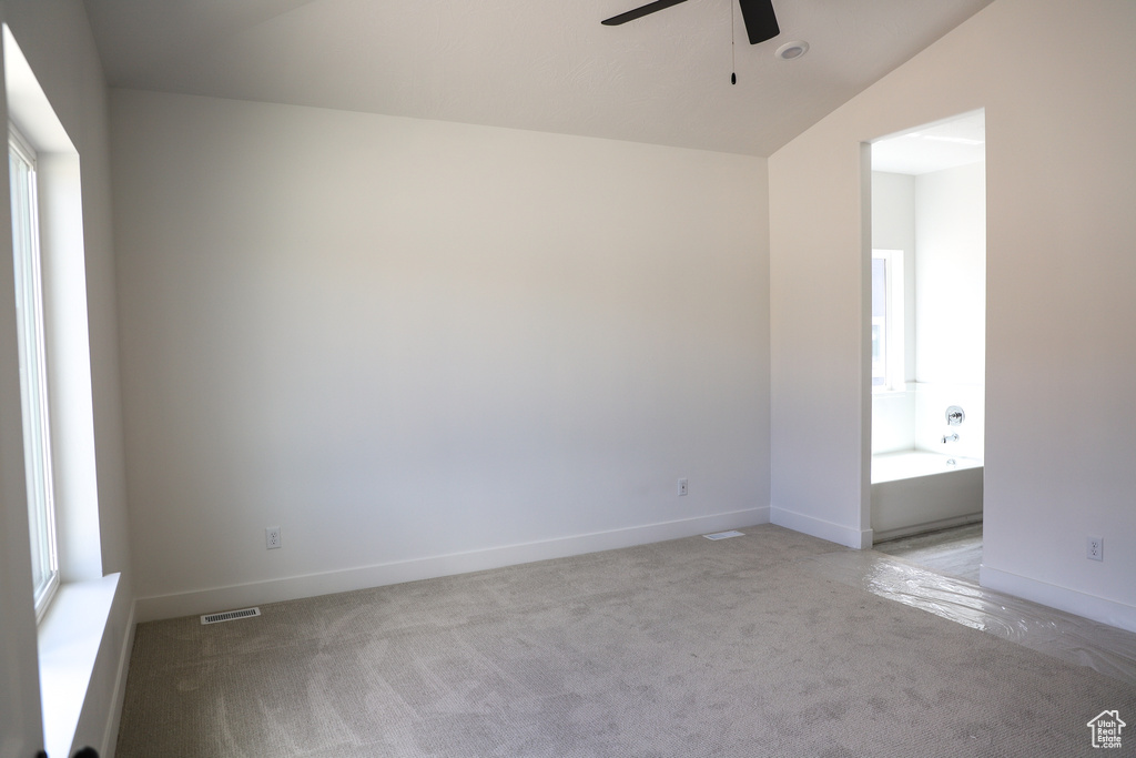 Unfurnished room with visible vents, baseboards, ceiling fan, and light colored carpet