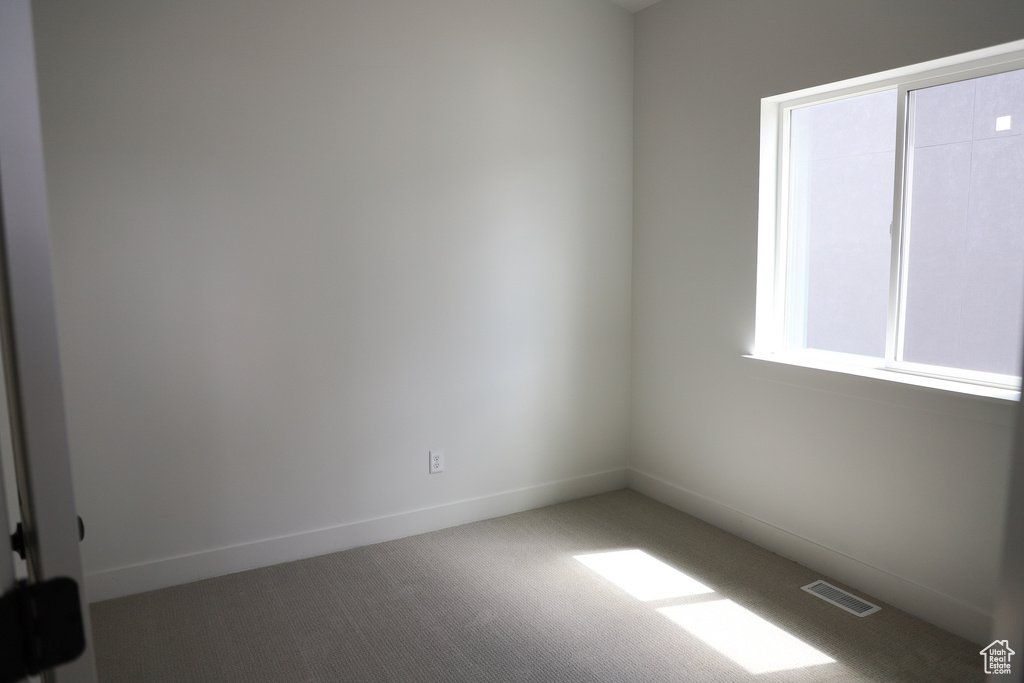 Carpeted empty room with baseboards and visible vents