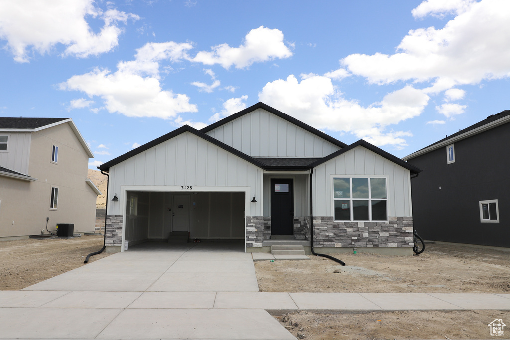 Modern farmhouse with an attached garage, board and batten siding, driveway, and stone siding