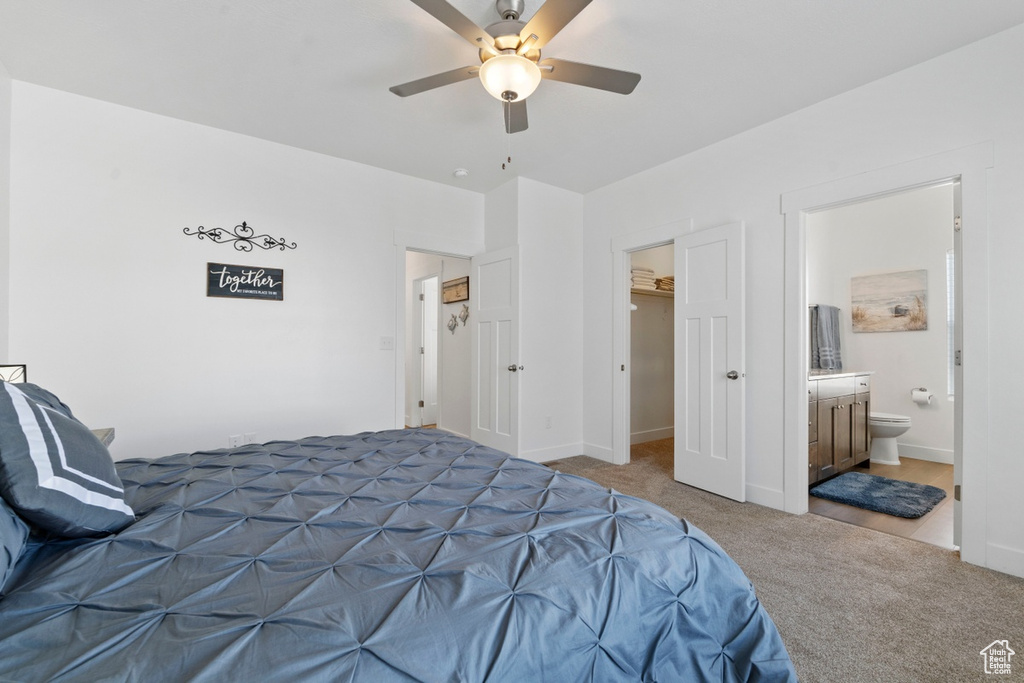 Carpeted bedroom with a closet, baseboards, a walk in closet, ceiling fan, and connected bathroom