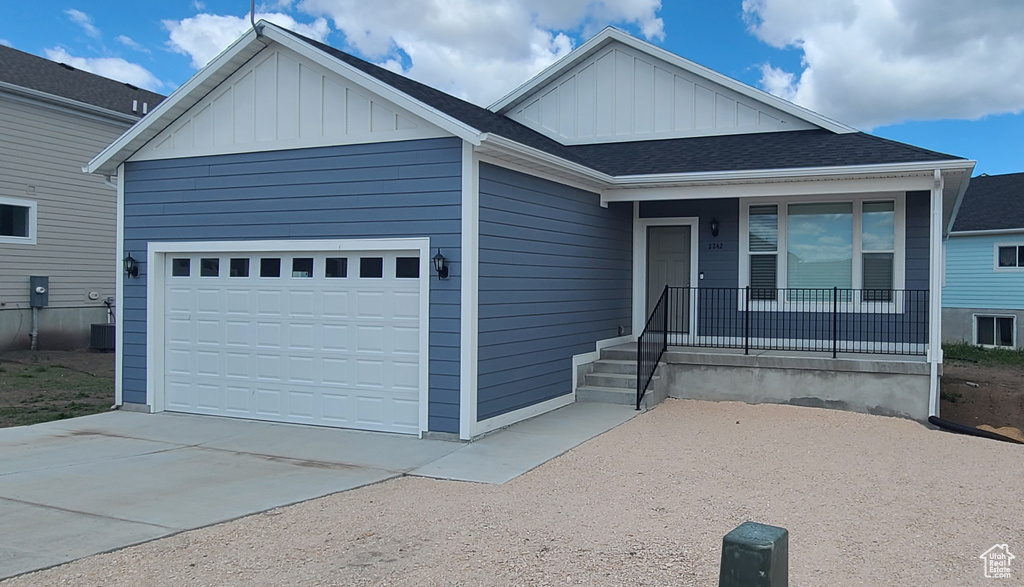 Single story home with a garage, board and batten siding, driveway, and covered porch