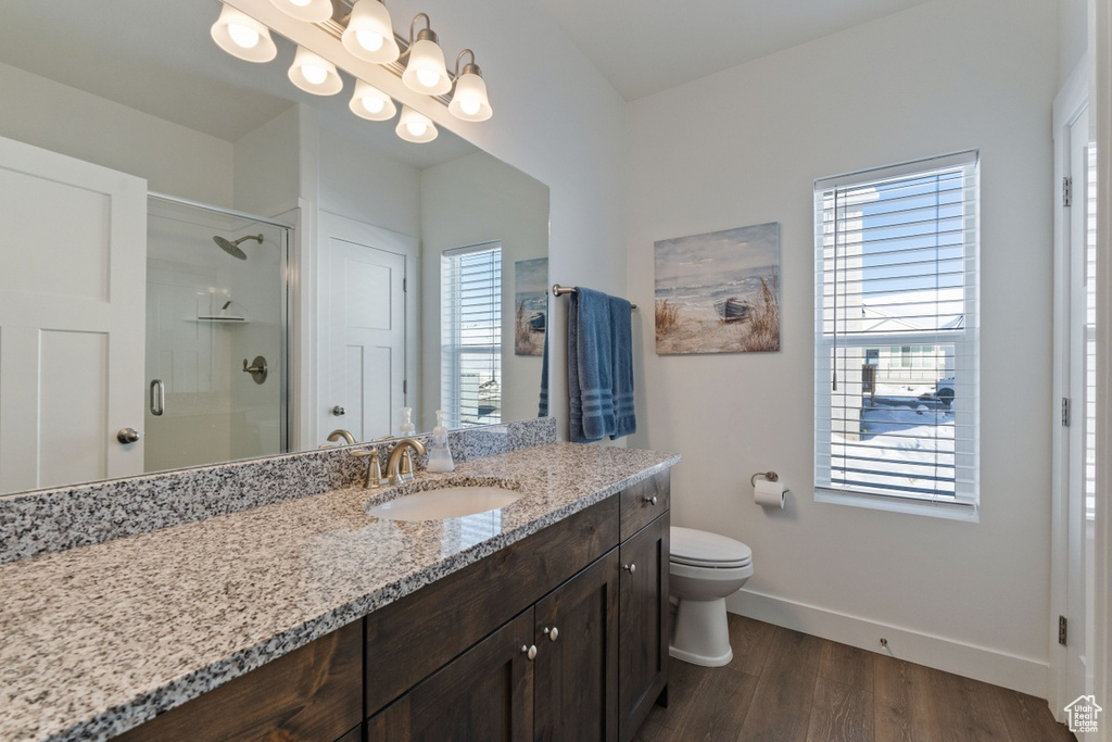 Bathroom with baseboards, a shower stall, wood finished floors, and plenty of natural light
