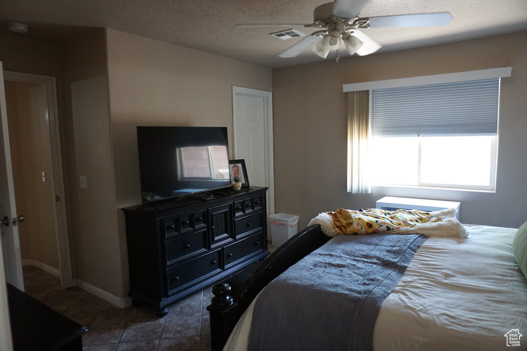 Tiled bedroom with a ceiling fan and visible vents