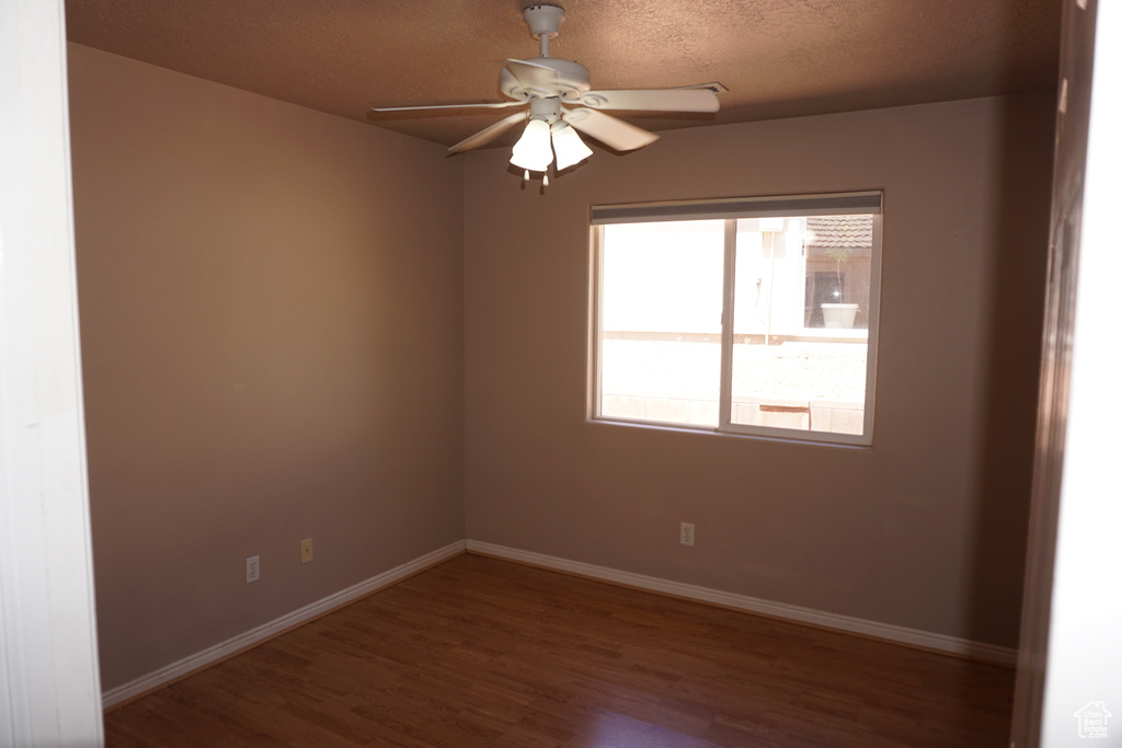 Empty room with wood finished floors, baseboards, and a ceiling fan