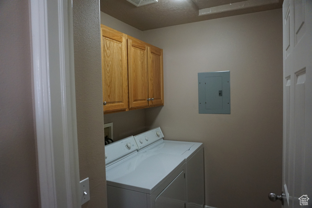 Washroom featuring independent washer and dryer, cabinet space, and electric panel