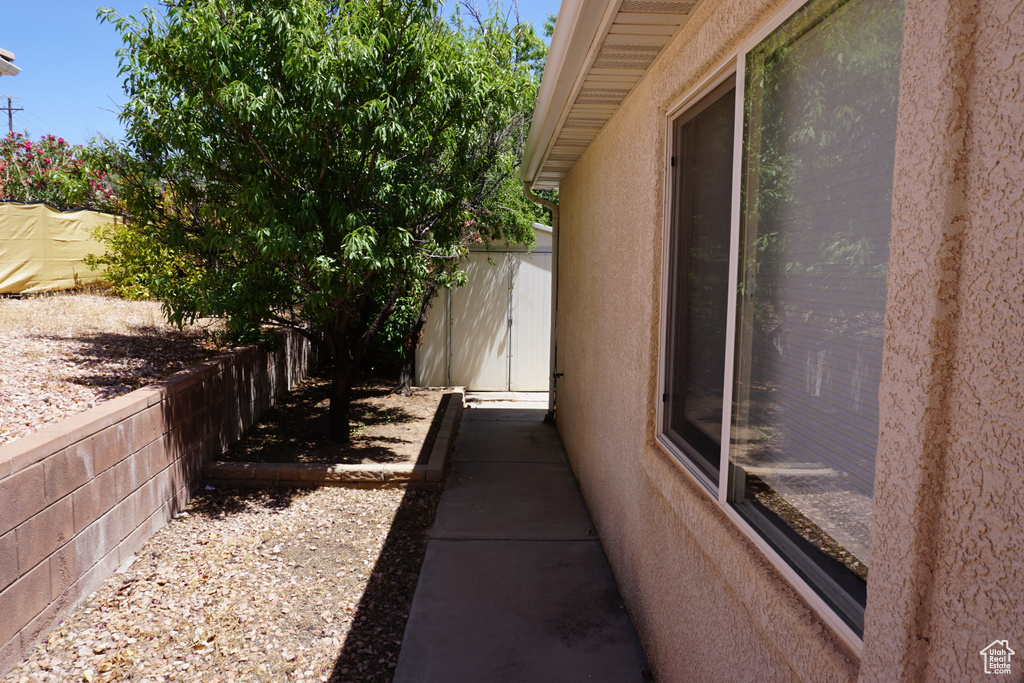 View of home's exterior with fence, stucco siding, a shed, and an outdoor structure