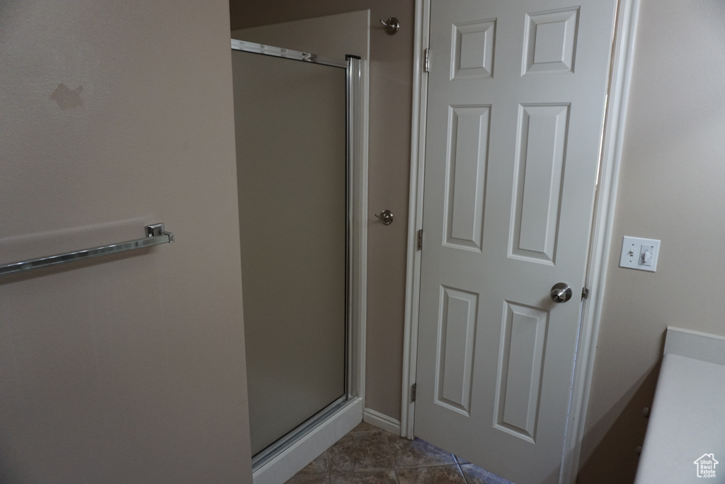 Full bath featuring a stall shower, tile patterned floors, and baseboards