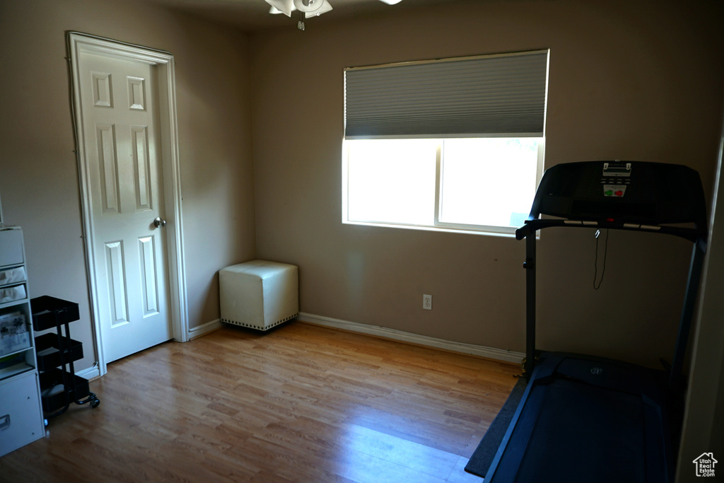 Exercise room with baseboards, a ceiling fan, and wood finished floors