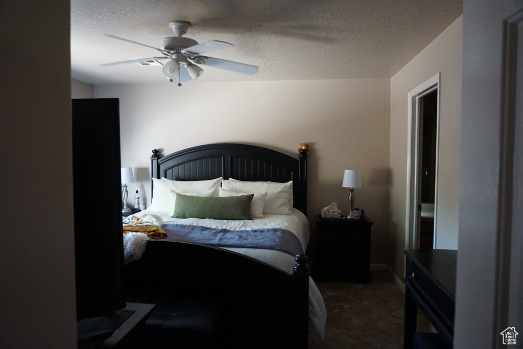 Bedroom with tile patterned flooring, a ceiling fan, and a textured ceiling