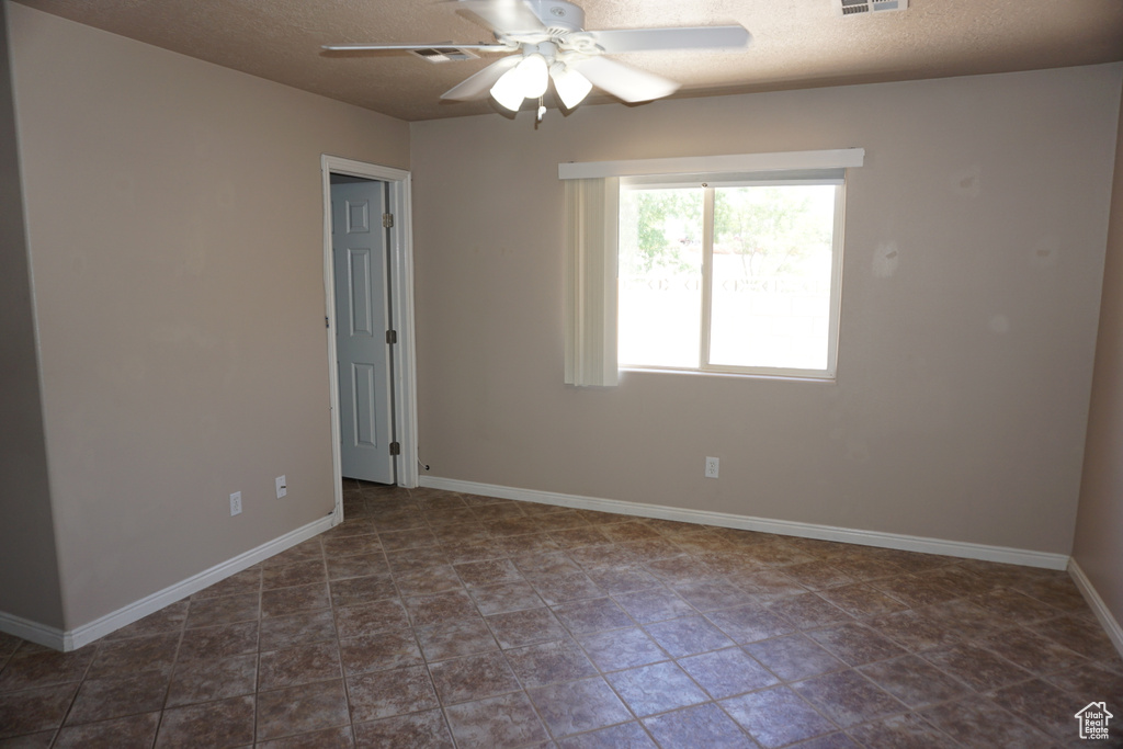Spare room with a ceiling fan, baseboards, and a textured ceiling