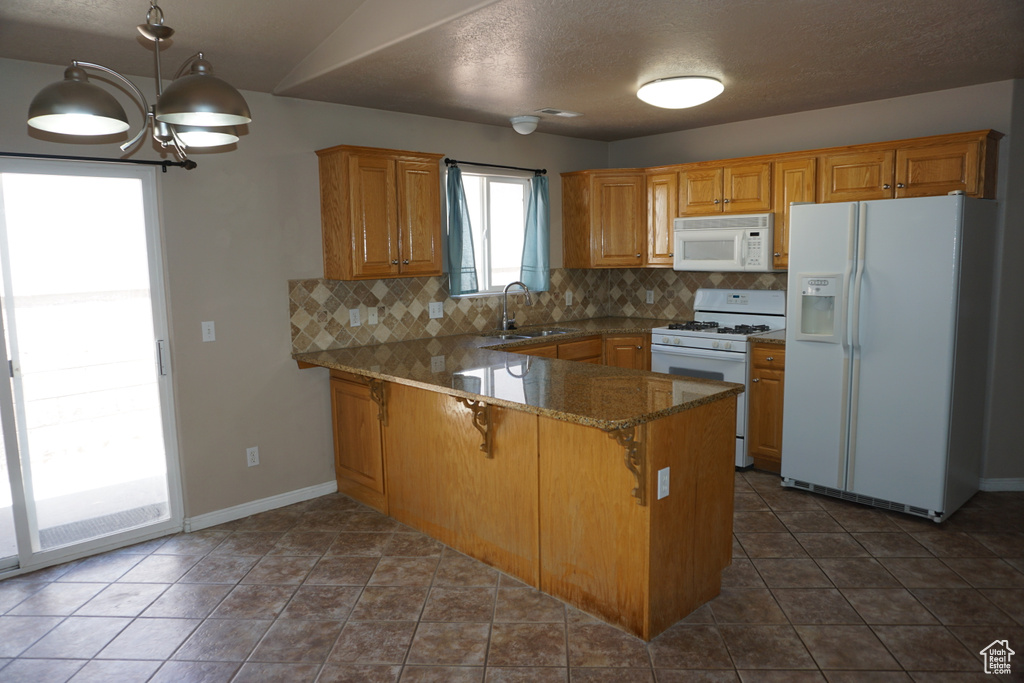 Kitchen with white appliances, a sink, decorative backsplash, a peninsula, and a breakfast bar