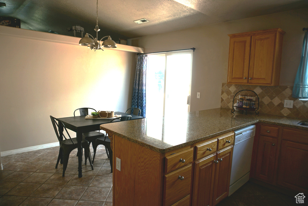 Kitchen with visible vents, white dishwasher, tasteful backsplash, a peninsula, and a notable chandelier