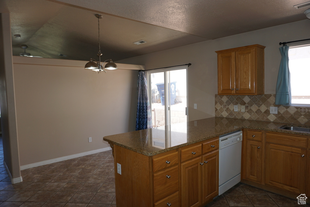 Kitchen with dishwasher, a chandelier, a peninsula, brown cabinets, and backsplash