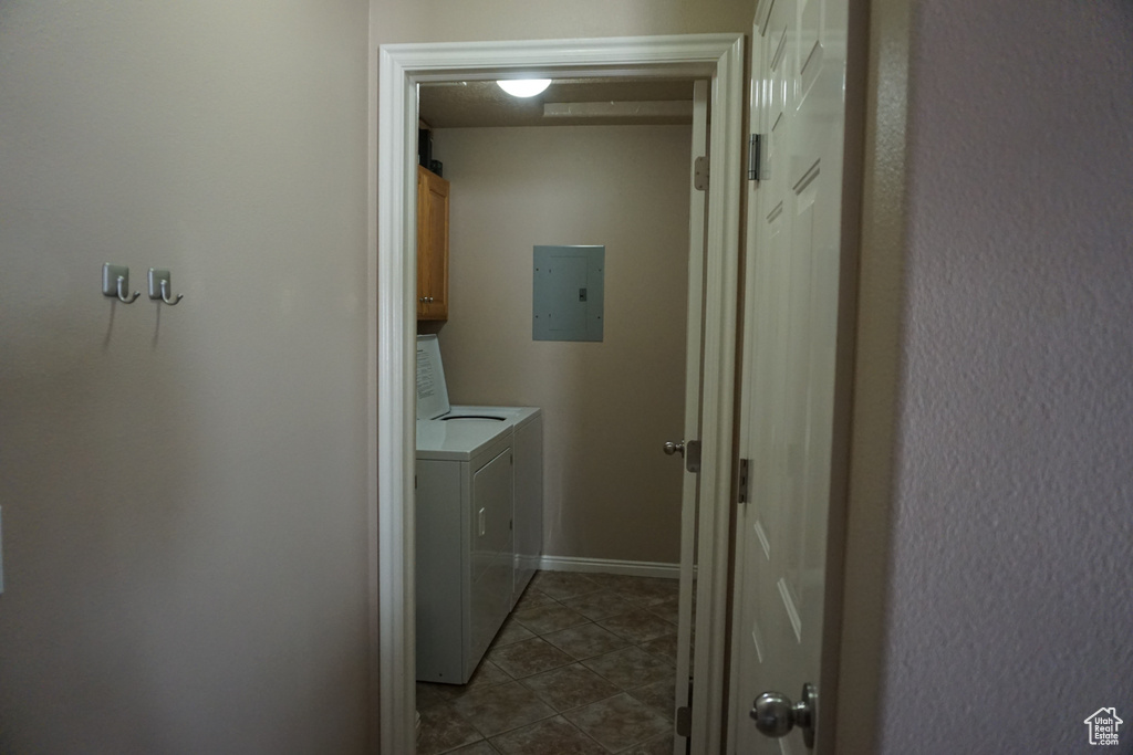 Washroom featuring tile patterned floors, cabinet space, washing machine and dryer, and electric panel