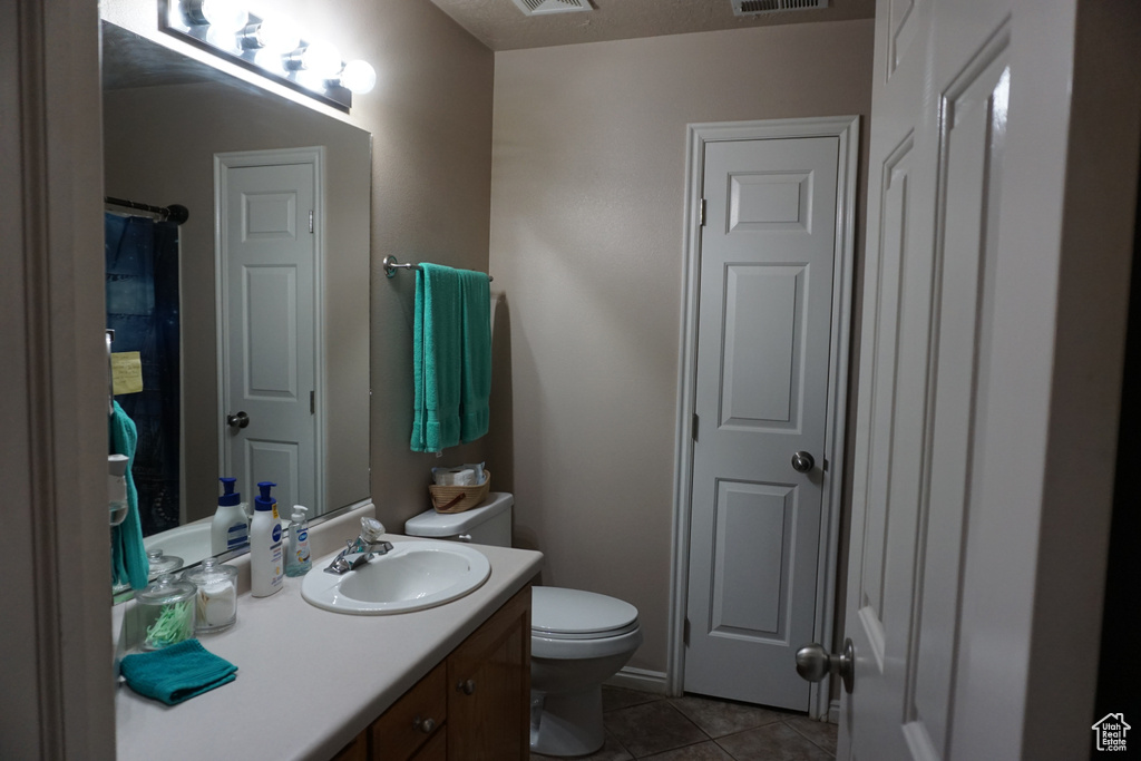 Bathroom featuring vanity, tile patterned flooring, toilet, and visible vents