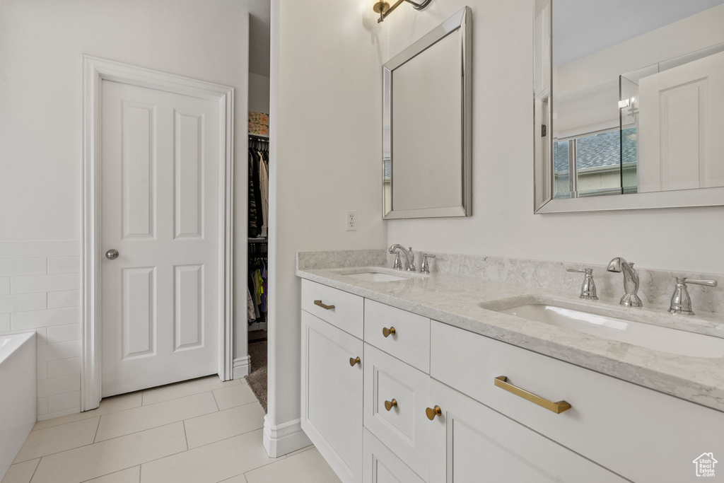 Bathroom with tile patterned flooring, a sink, a walk in closet, and double vanity