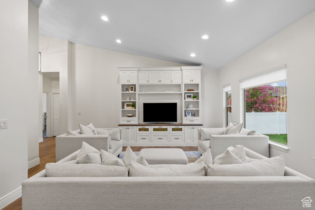 Living room with baseboards, vaulted ceiling, recessed lighting, and wood finished floors