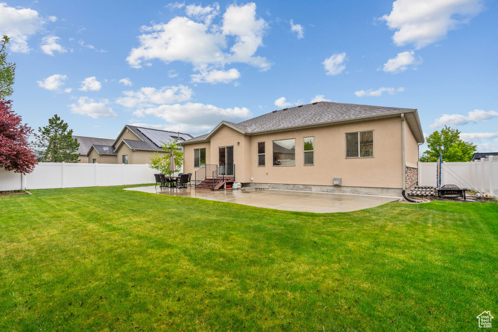Back of property featuring a lawn, a fenced backyard, a patio area, and stucco siding