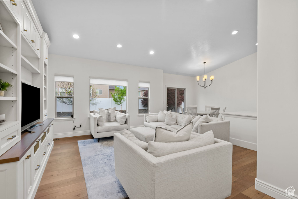 Living room featuring an inviting chandelier, recessed lighting, and light wood-style floors