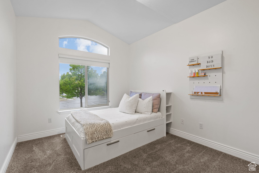 Bedroom with baseboards, vaulted ceiling, and dark carpet