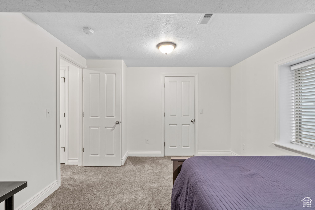 Bedroom with visible vents, carpet flooring, a textured ceiling, and baseboards