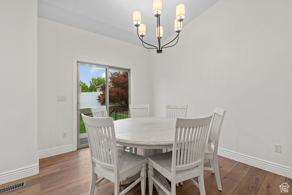 Dining space featuring visible vents, baseboards, a chandelier, and hardwood / wood-style flooring