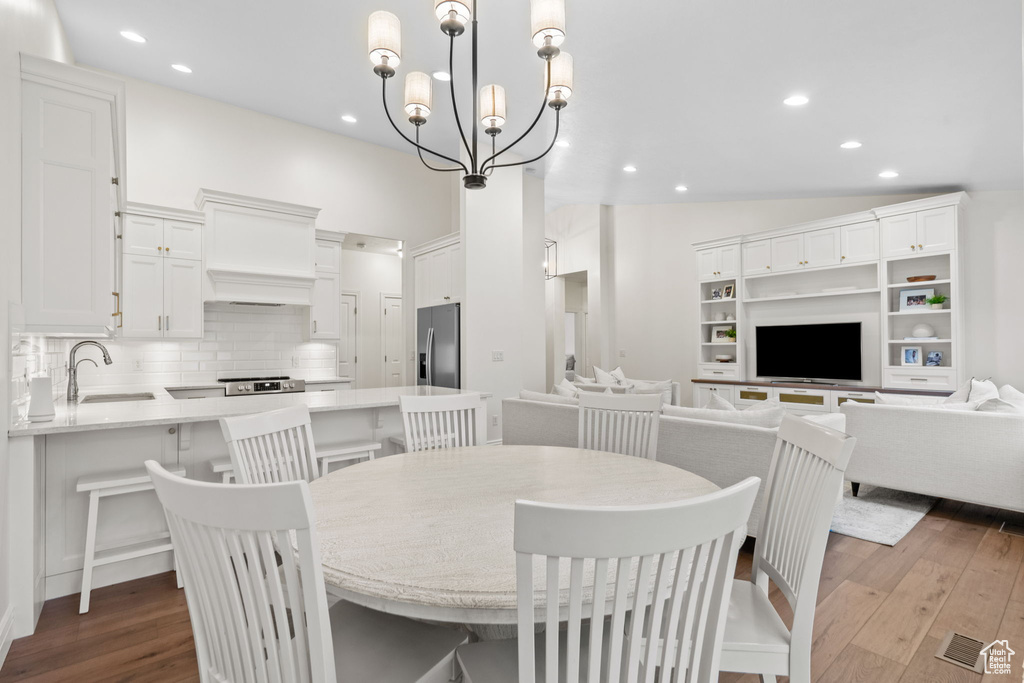 Dining area featuring recessed lighting, dark wood-style floors, vaulted ceiling, and an inviting chandelier