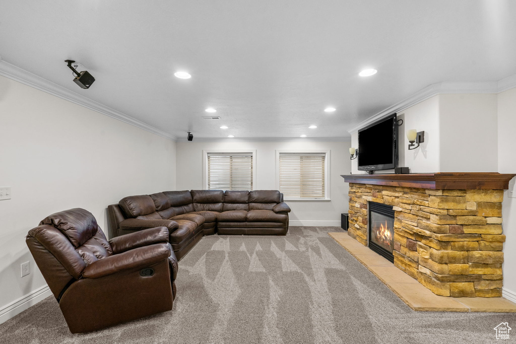Living area with light colored carpet, a stone fireplace, recessed lighting, baseboards, and ornamental molding