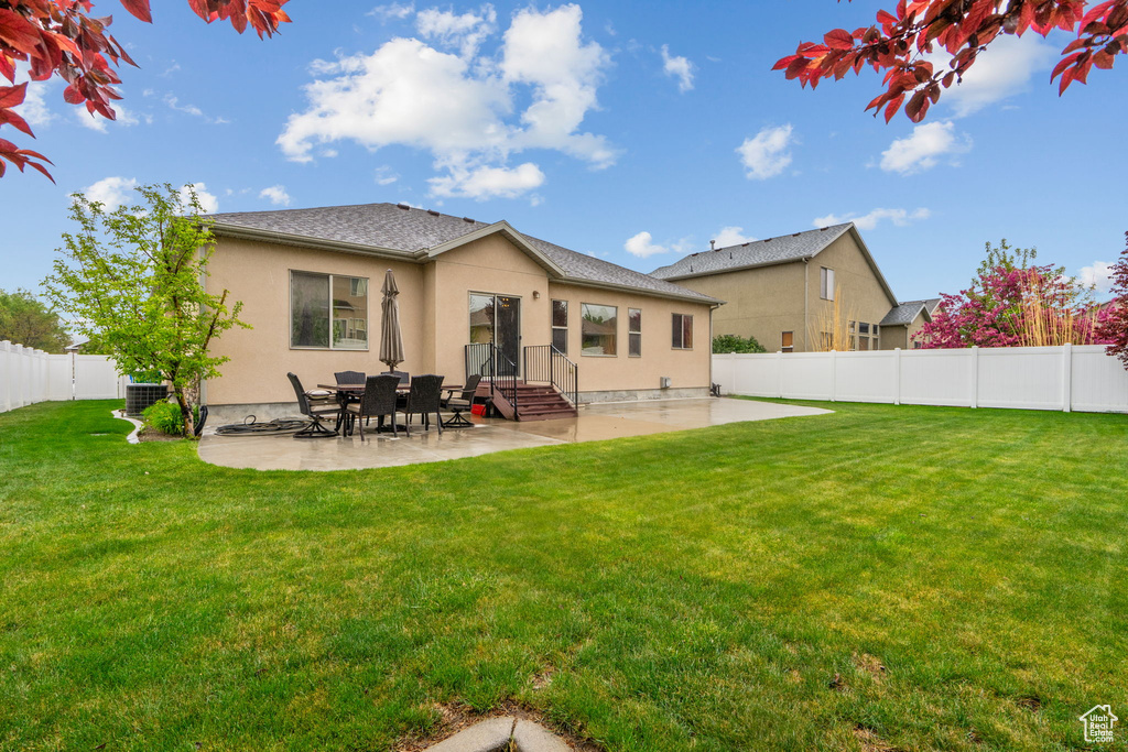 Rear view of house with a lawn, a fenced backyard, a patio area, and stucco siding
