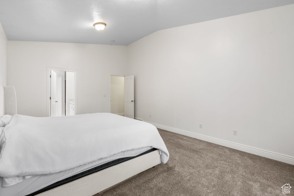Carpeted bedroom with baseboards and vaulted ceiling