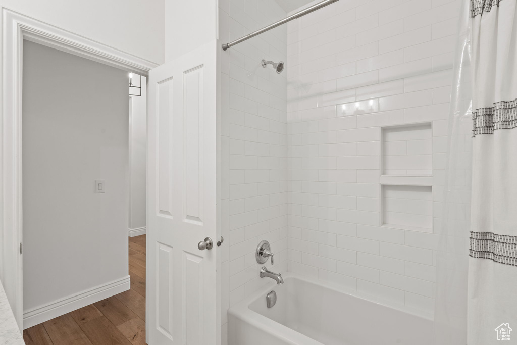 Bathroom featuring baseboards, wood finished floors, and shower / tub combo