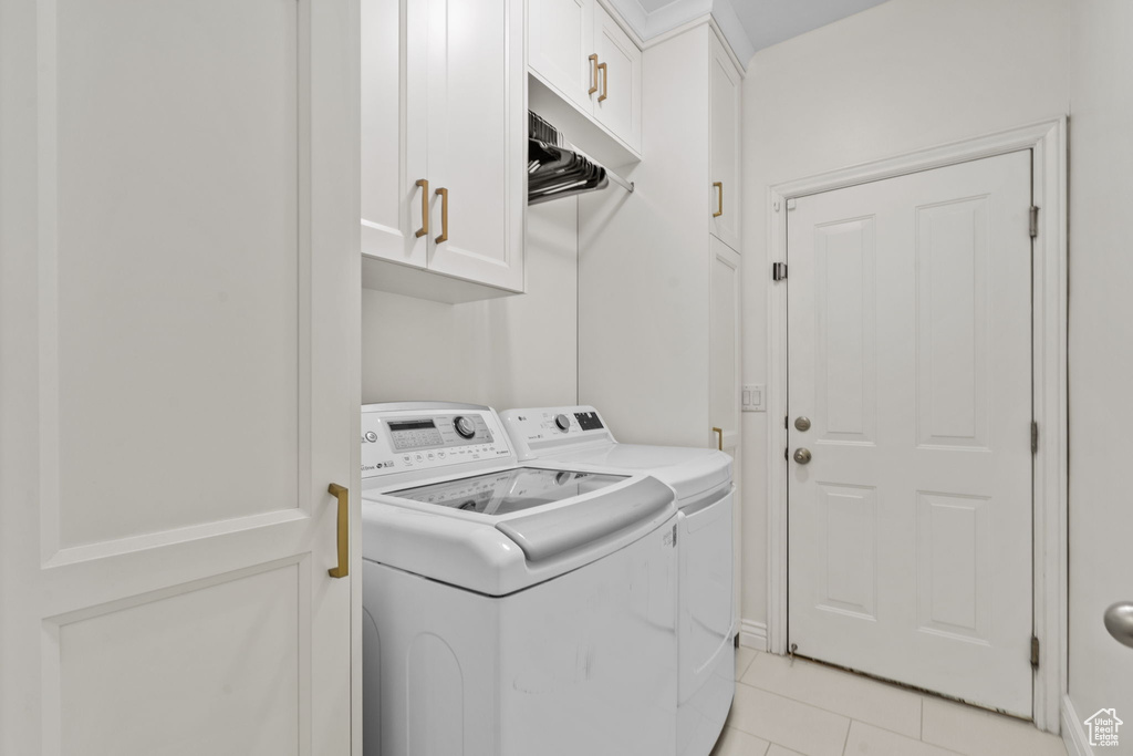 Laundry area featuring light tile patterned floors, cabinet space, and washer and clothes dryer