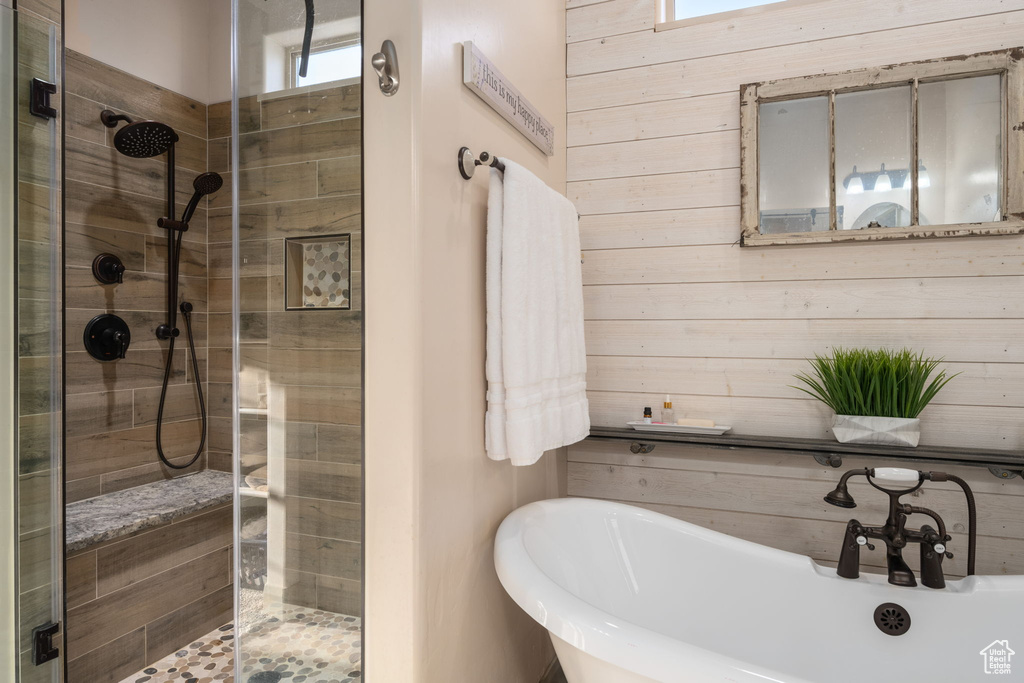 Bathroom featuring a sink, a freestanding tub, wooden walls, and a shower stall