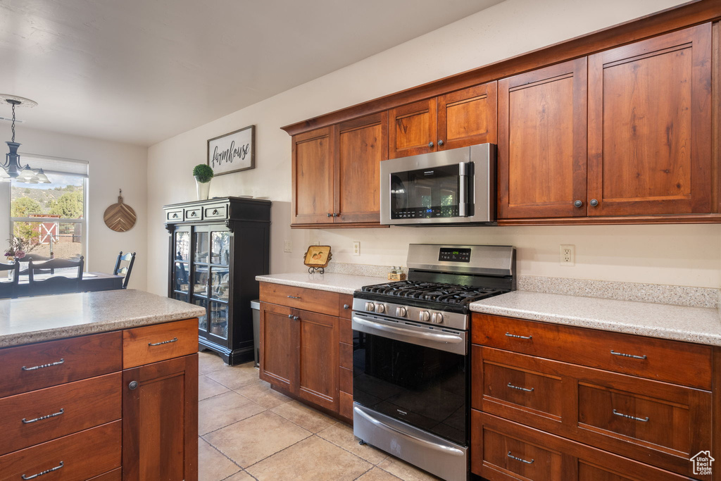 Kitchen featuring light countertops, light tile patterned floors, decorative light fixtures, and stainless steel appliances