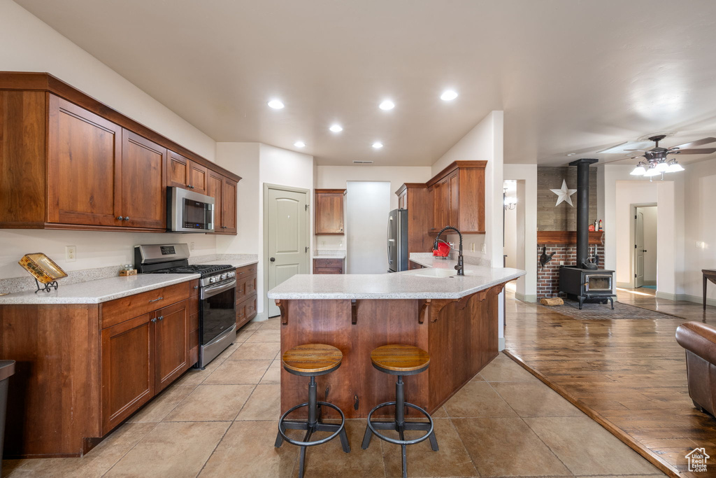 Kitchen with a wood stove, a breakfast bar area, light countertops, stainless steel appliances, and a peninsula