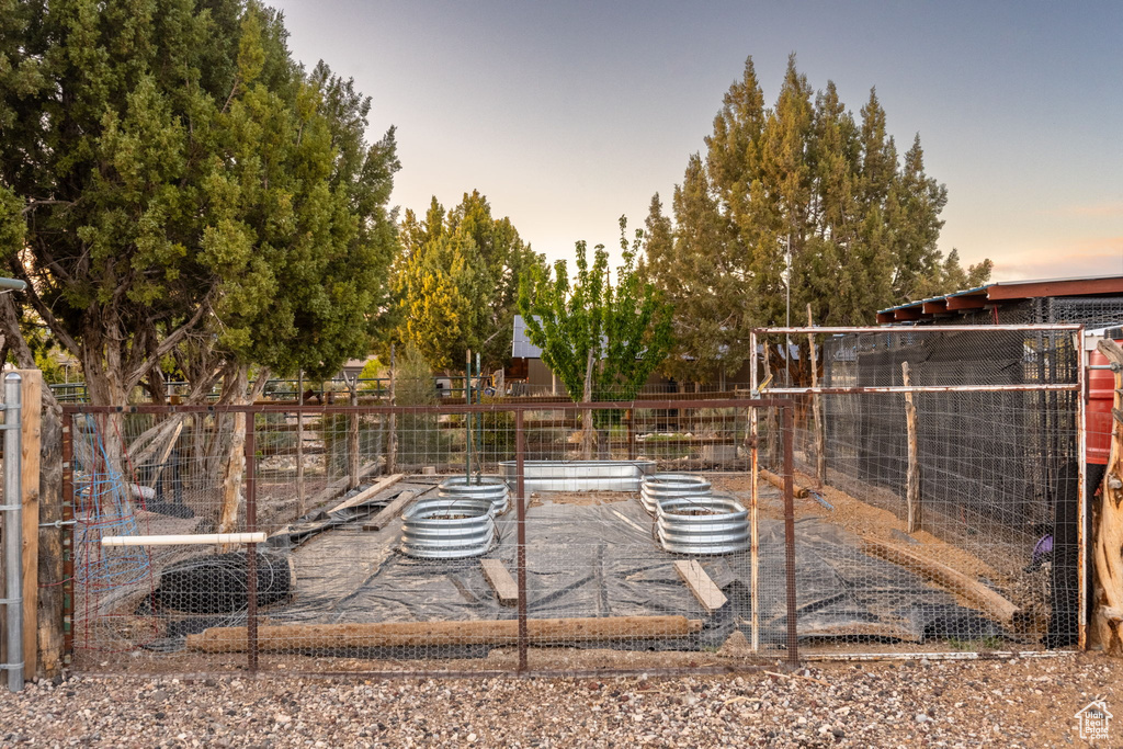 View of yard with fence, exterior structure, and a vegetable garden