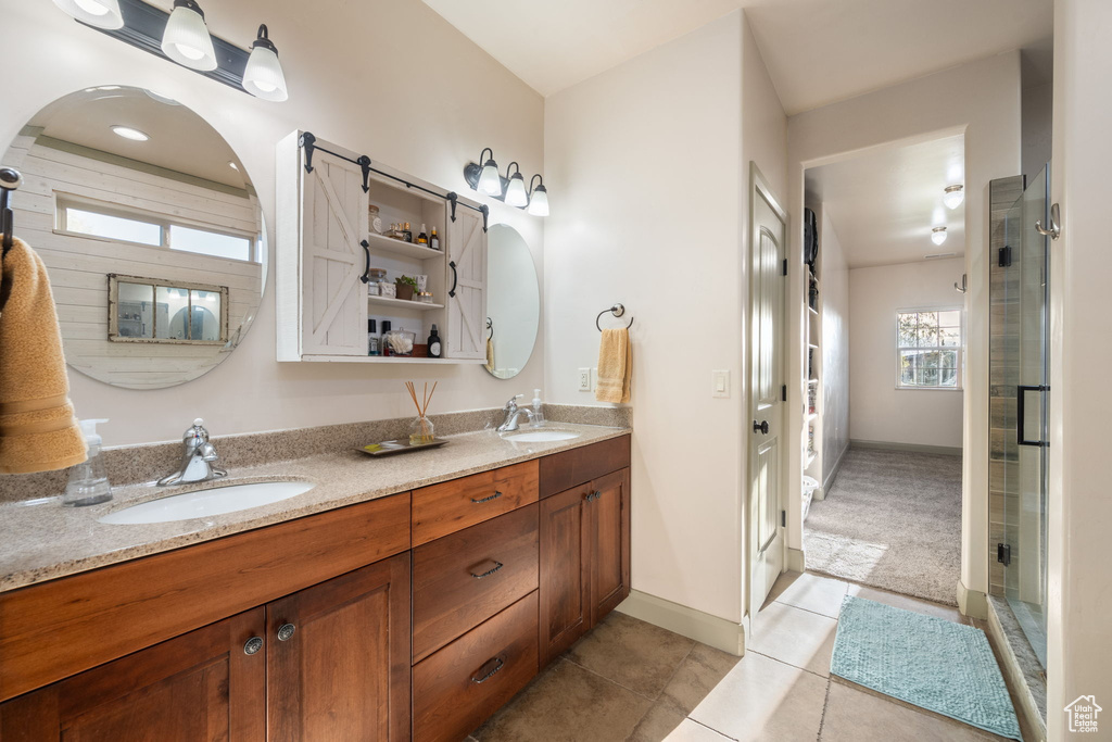 Full bath featuring double vanity, a shower stall, a sink, and tile patterned flooring