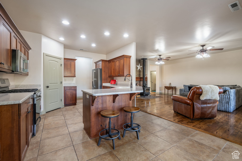 Kitchen with visible vents, a peninsula, a breakfast bar, open floor plan, and appliances with stainless steel finishes