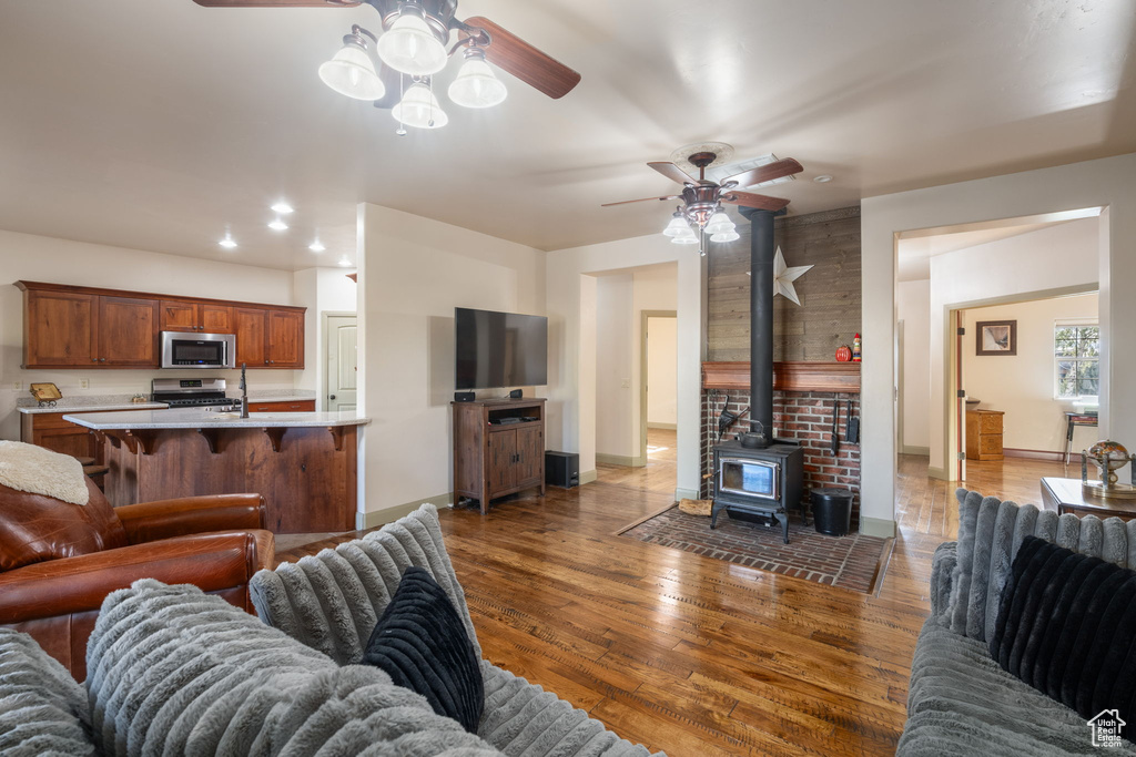 Living room with ceiling fan, baseboards, a wood stove, and hardwood / wood-style floors