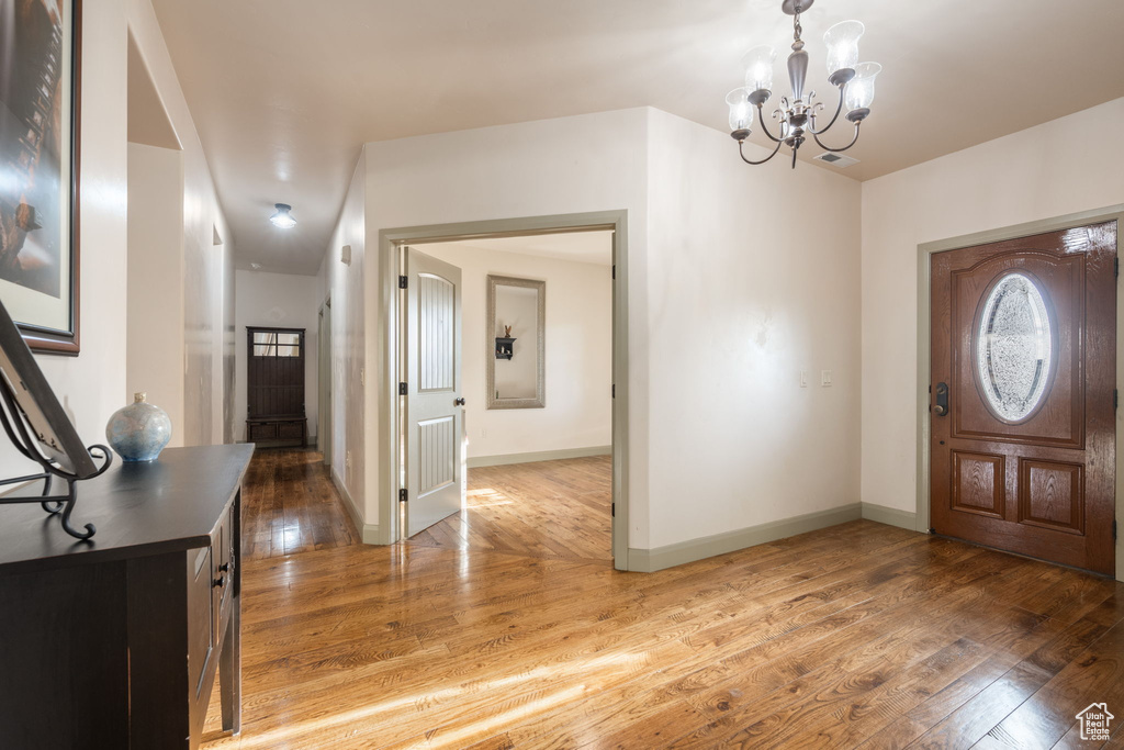 Foyer with baseboards, visible vents, light wood-style flooring, and a notable chandelier