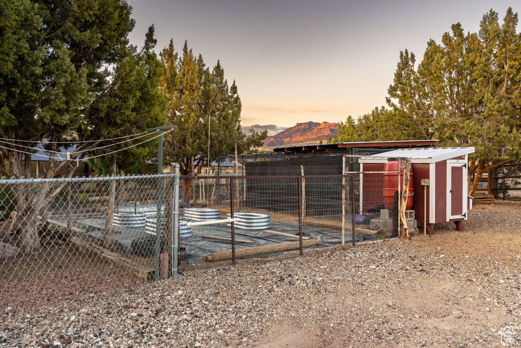 Outdoor structure at dusk with exterior structure, fence, a mountain view, and an outdoor structure